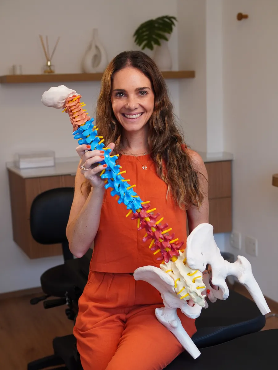 Janaína Butafava segurando um modelo anatômico da coluna vertebral